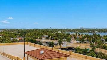 Una terraza con tejado de baldosas y vistas a una ciudad costera con palmeras y edificios.