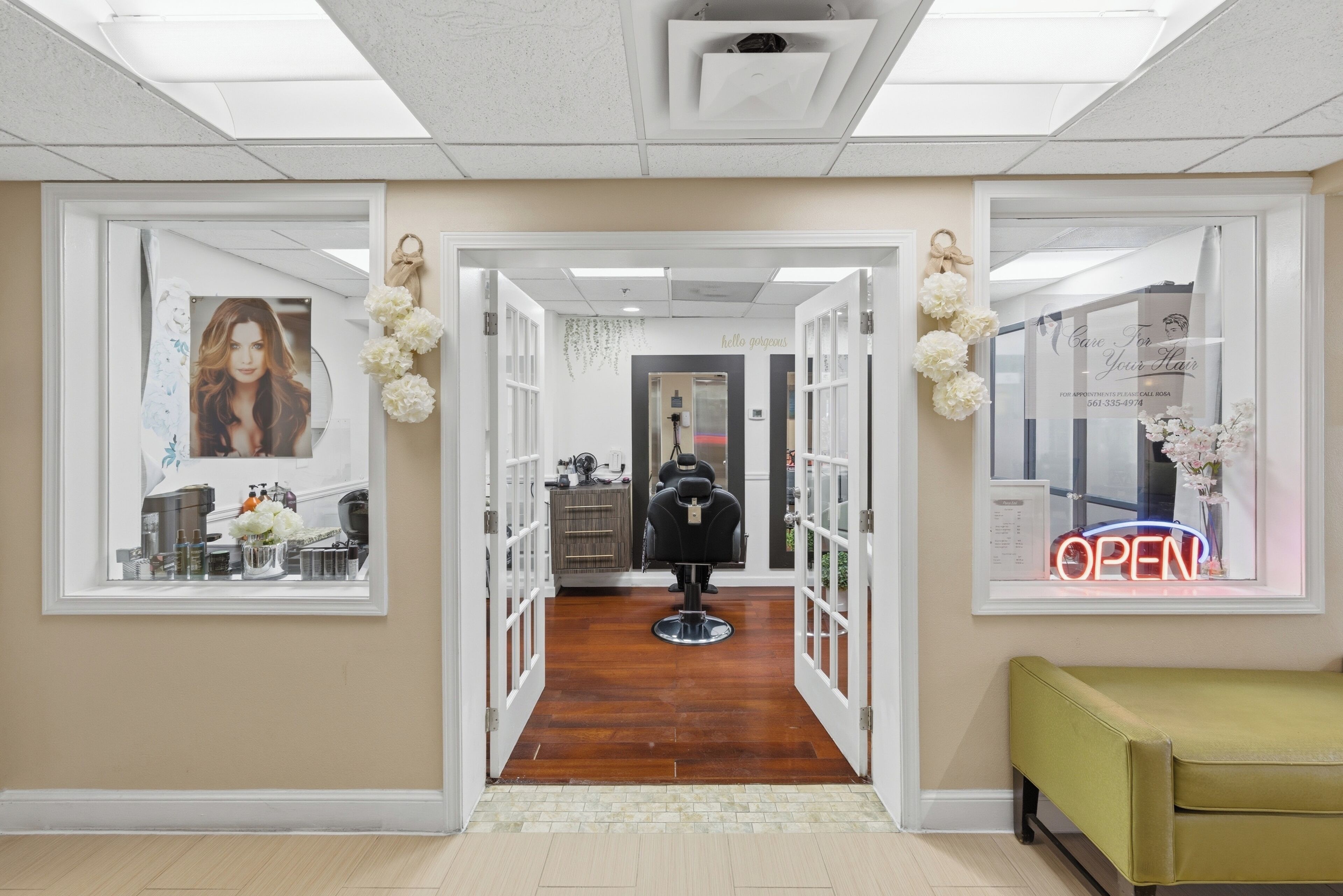 L’intérieur d’un salon de coiffure, avec un comptoir d’accueil, un fauteuil de coiffure et un panneau néon indiquant « OUVERT ».