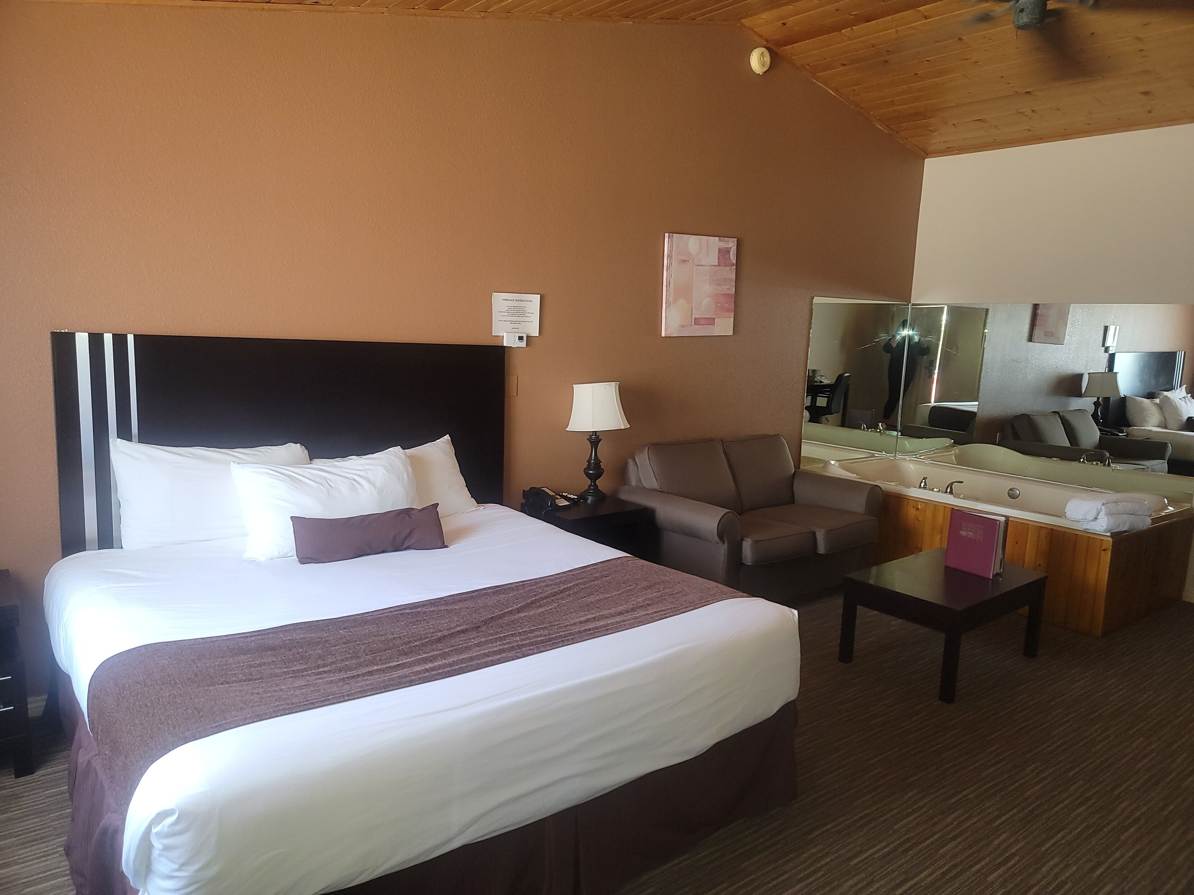 Habitación de hotel con una cama grande, un escritorio, una silla, un espejo y un área de baño.