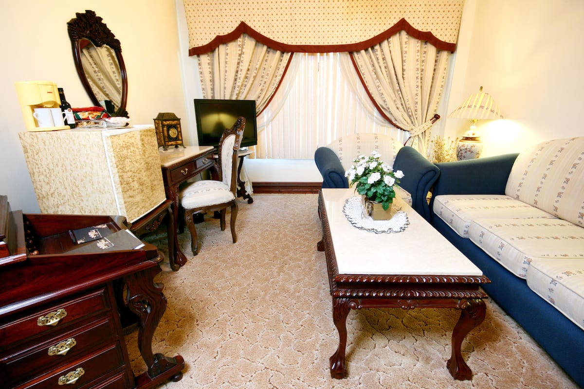 A traditional living room with a sofa, a coffee table, a desk, and a television.