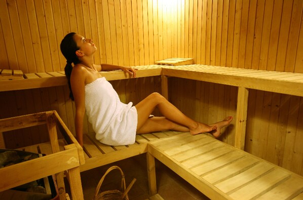 A person in a wooden sauna with benches and a bench seat.