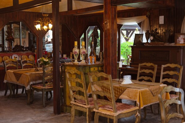 A dining area with wooden tables and chairs, a chandelier, and various decorative items.