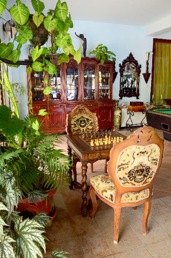 A room with a wooden chess table, a decorative chair, and a large cabinet with glass doors.