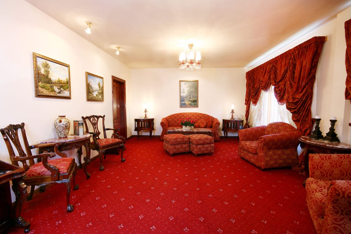 A room with a red carpet, wooden furniture, and paintings on the walls.