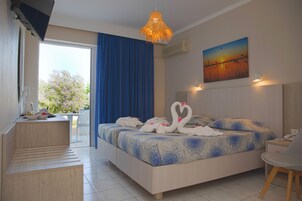 Habitación de hotel con cama, escritorio, silla, un cuadro y vistas al exterior.