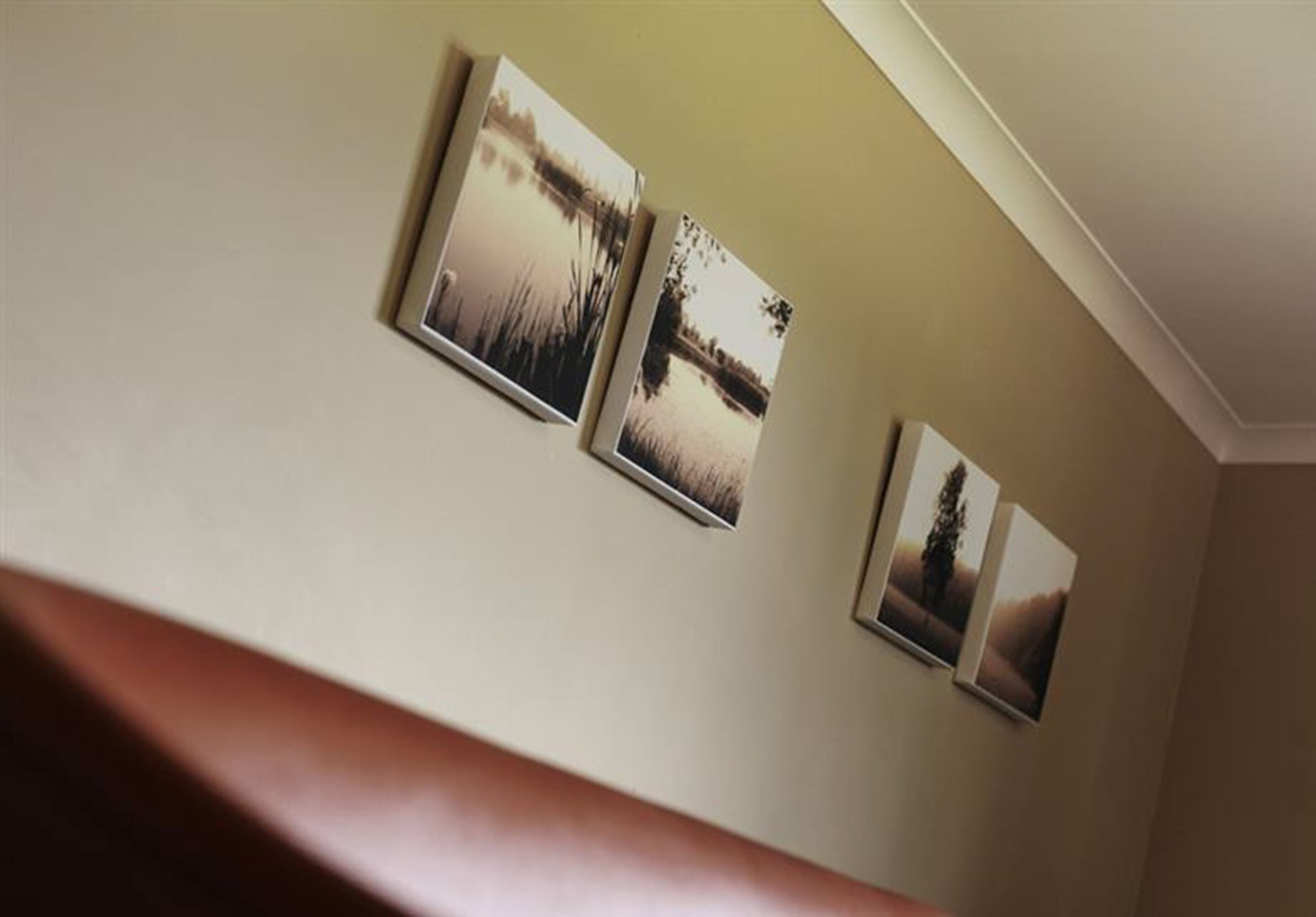 A staircase with a brown handrail and three framed photographs on the wall.