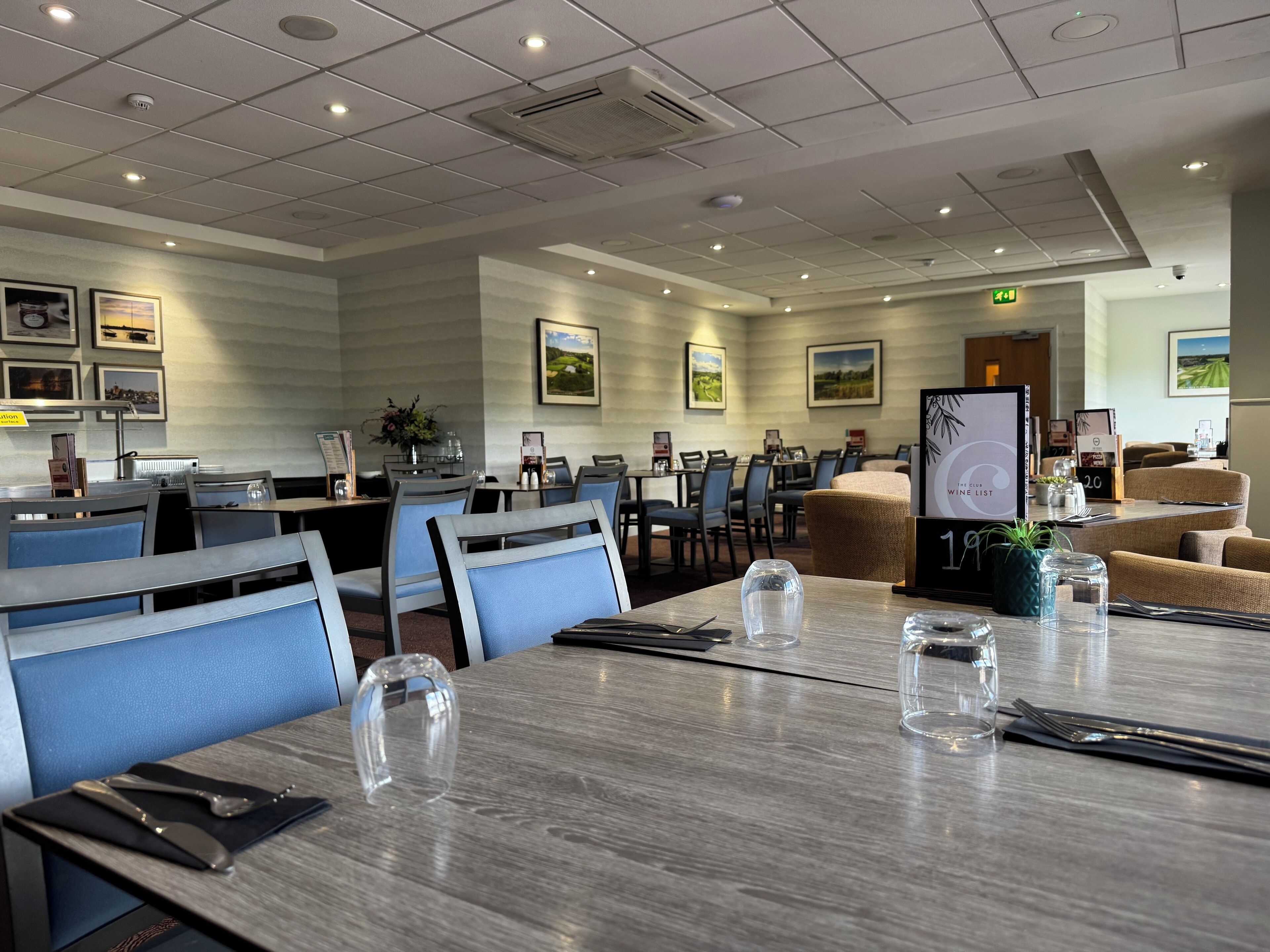 A hotel dining area with tables set for dining, chairs, and a menu stand.