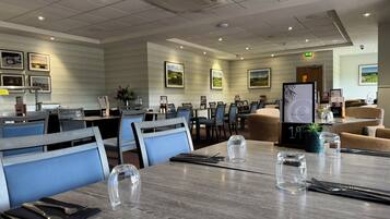 Un comedor de hotel con mesas dispuestas para comer, sillas y un atril para el menú.