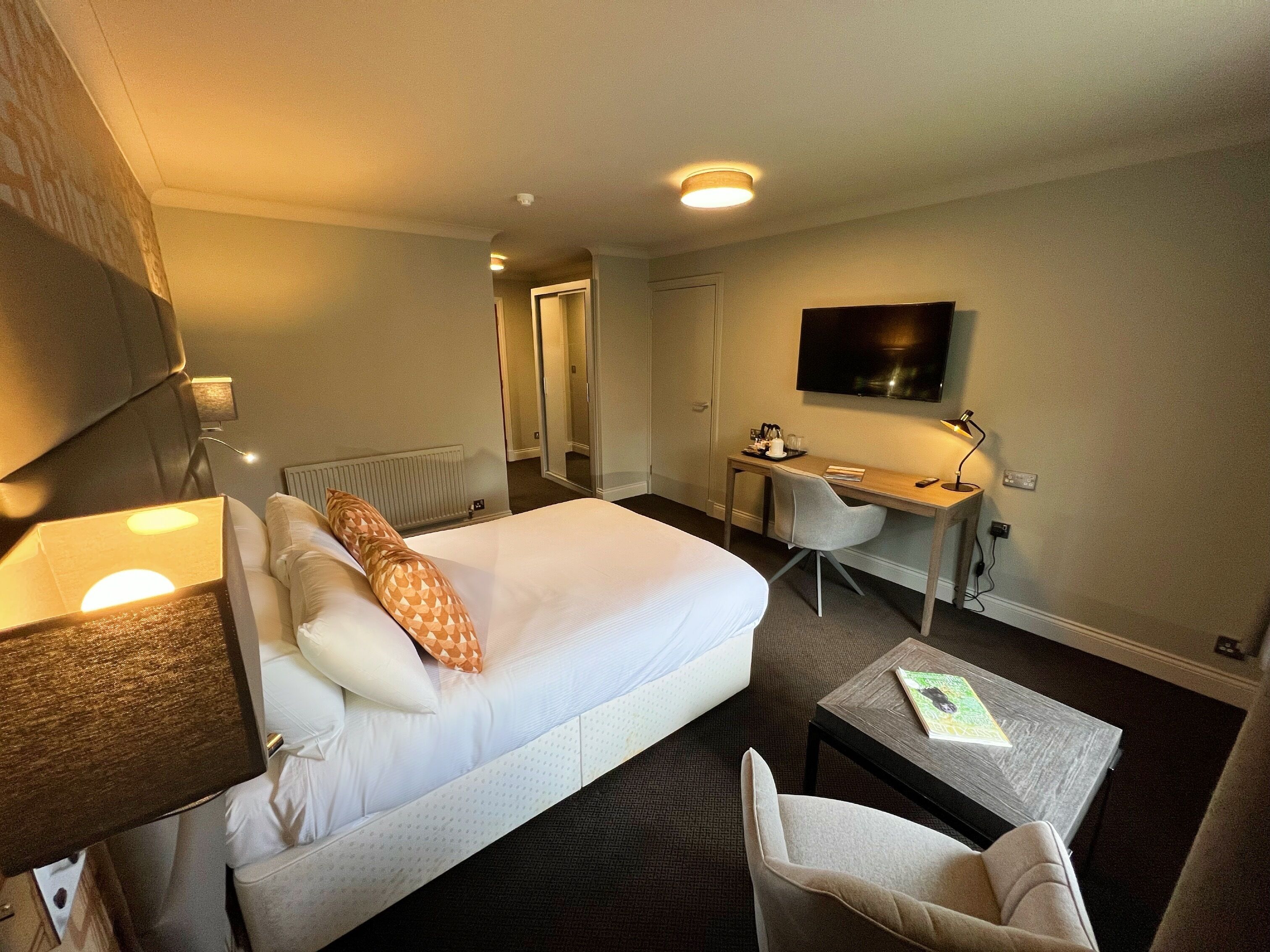 Una habitación de hotel con una cama, un escritorio, una silla, un televisor y una lámpara.