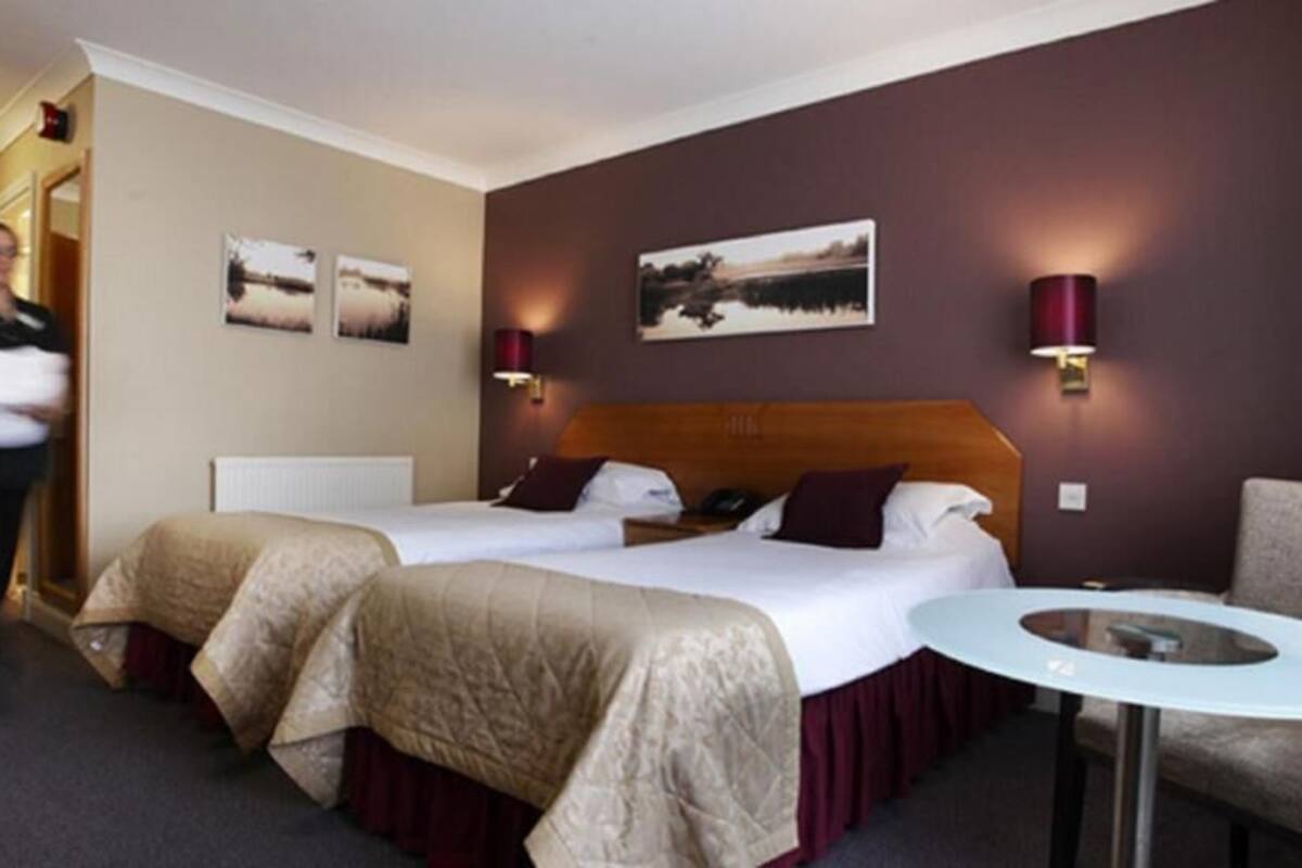 Une chambre d’hôtel avec deux lits, une table ronde et une chaise.