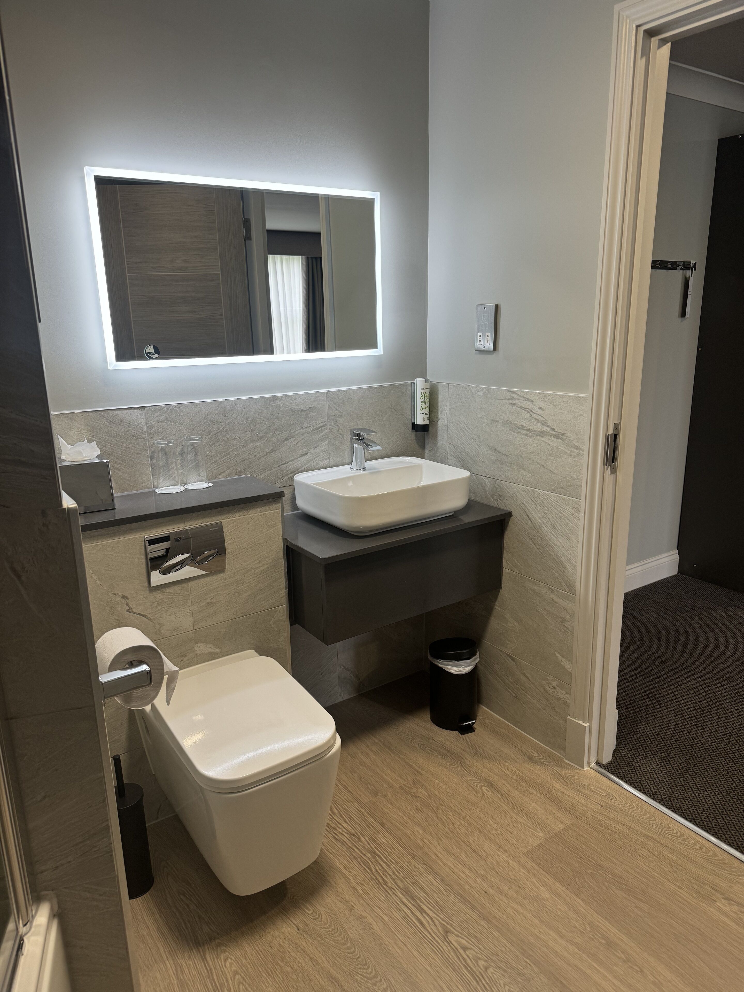 A modern bathroom with a toilet, sink, and mirror.