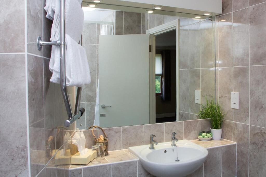 Un baño moderno con un espejo grande, un lavabo y una zona de ducha.