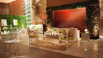 A modern lobby with a seating area, a bar, and a green wall with plants.
