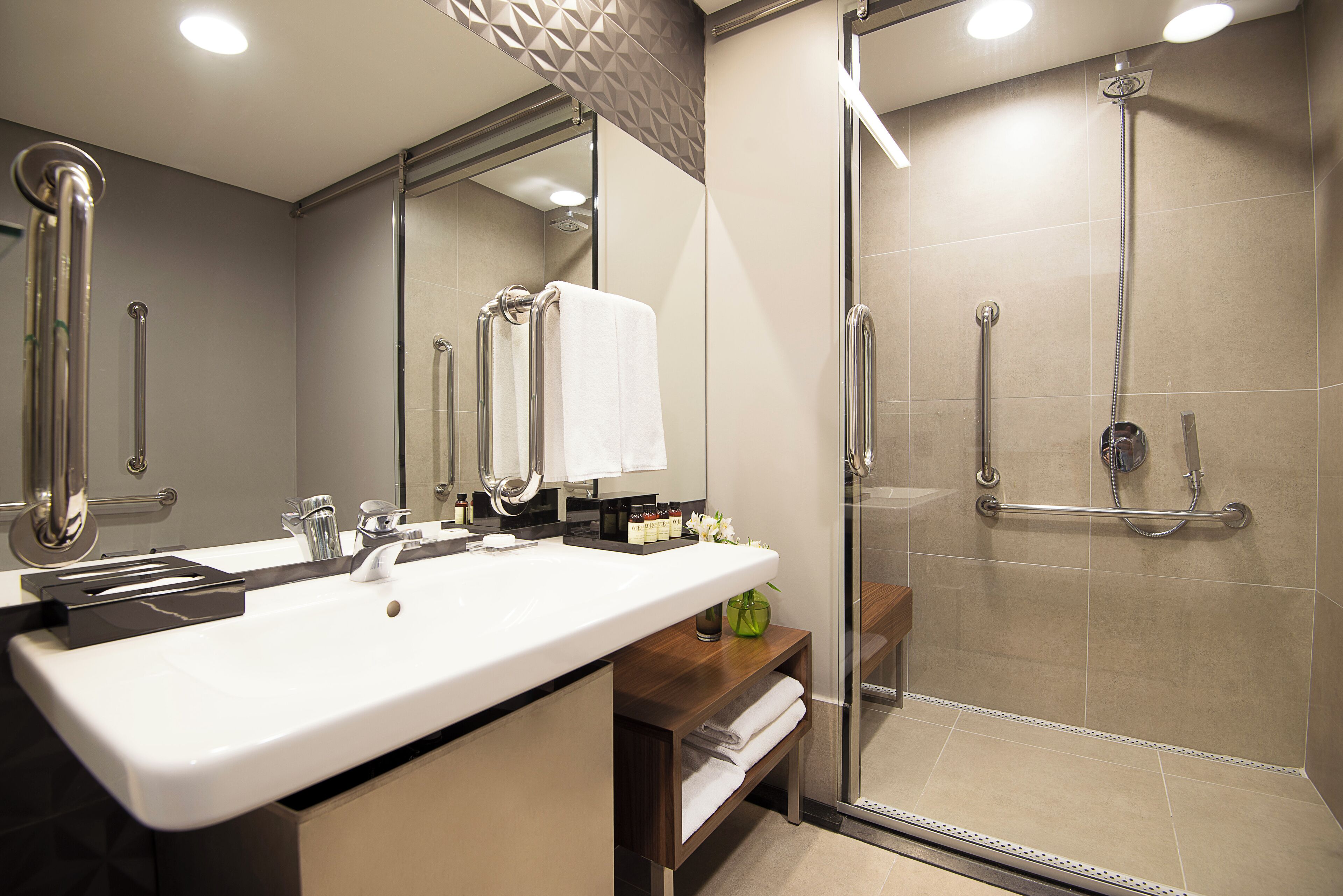A modern bathroom with a large sink, mirror, and glass shower enclosure.