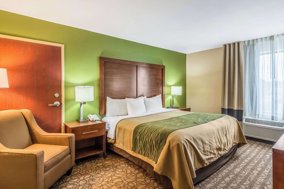 Une chambre d’hôtel avec un lit, une chaise, un bureau et une lampe.