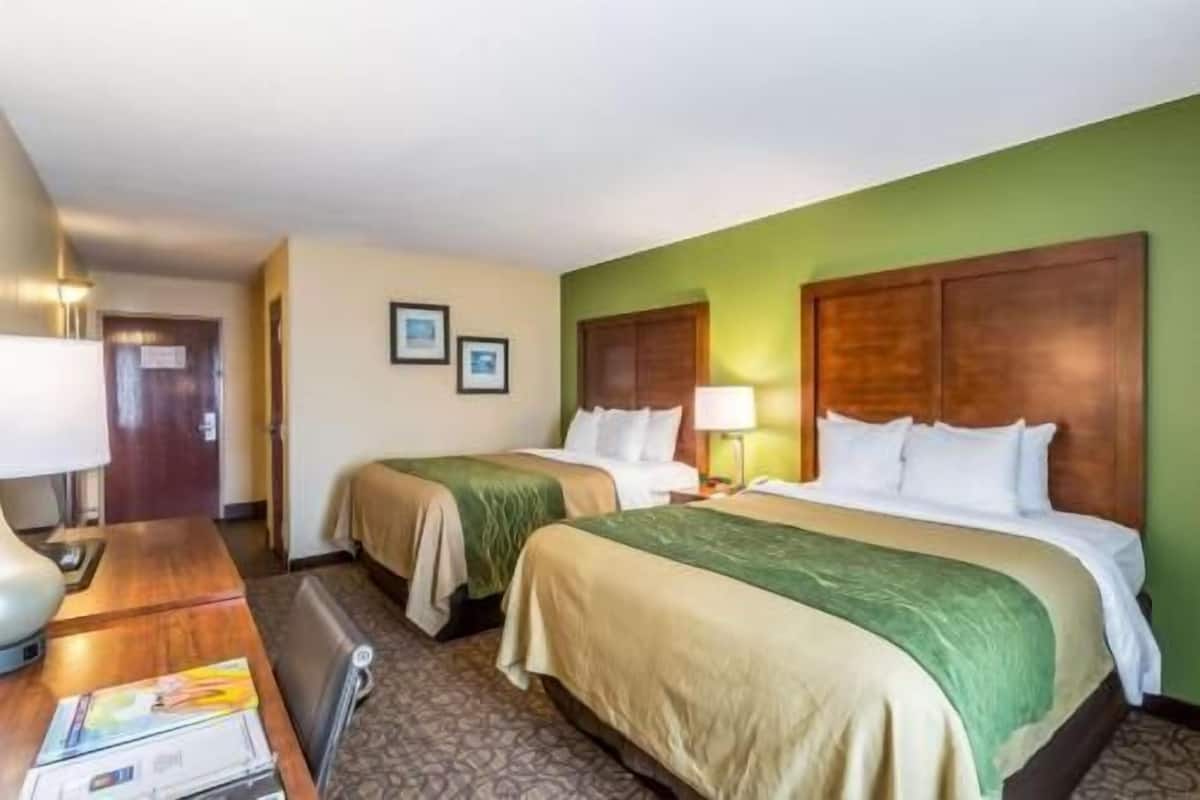 Une chambre d’hôtel avec deux lits, un bureau et une chaise.