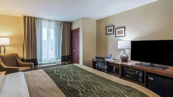 Ein Hotelzimmer mit Bett, Schreibtisch, Stuhl, Fernseher, Mikrowelle und einer Tür.