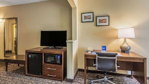 Hotelkamer met een bureau, stoel, televisie, minibar, magnetron en een lamp.