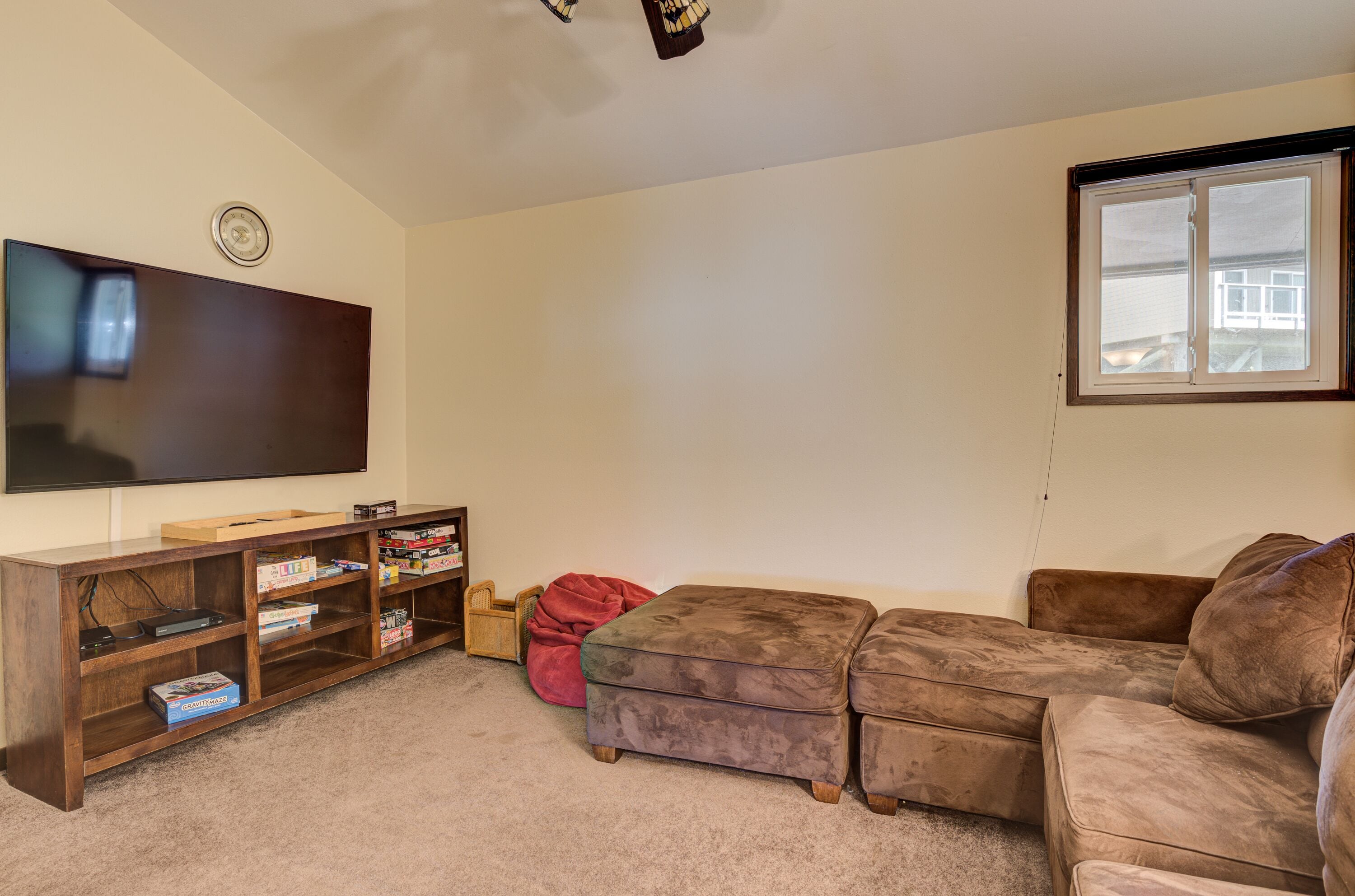 Een woonkamer met een flatscreen televisie, een houten tv-meubel en een hoekbank.