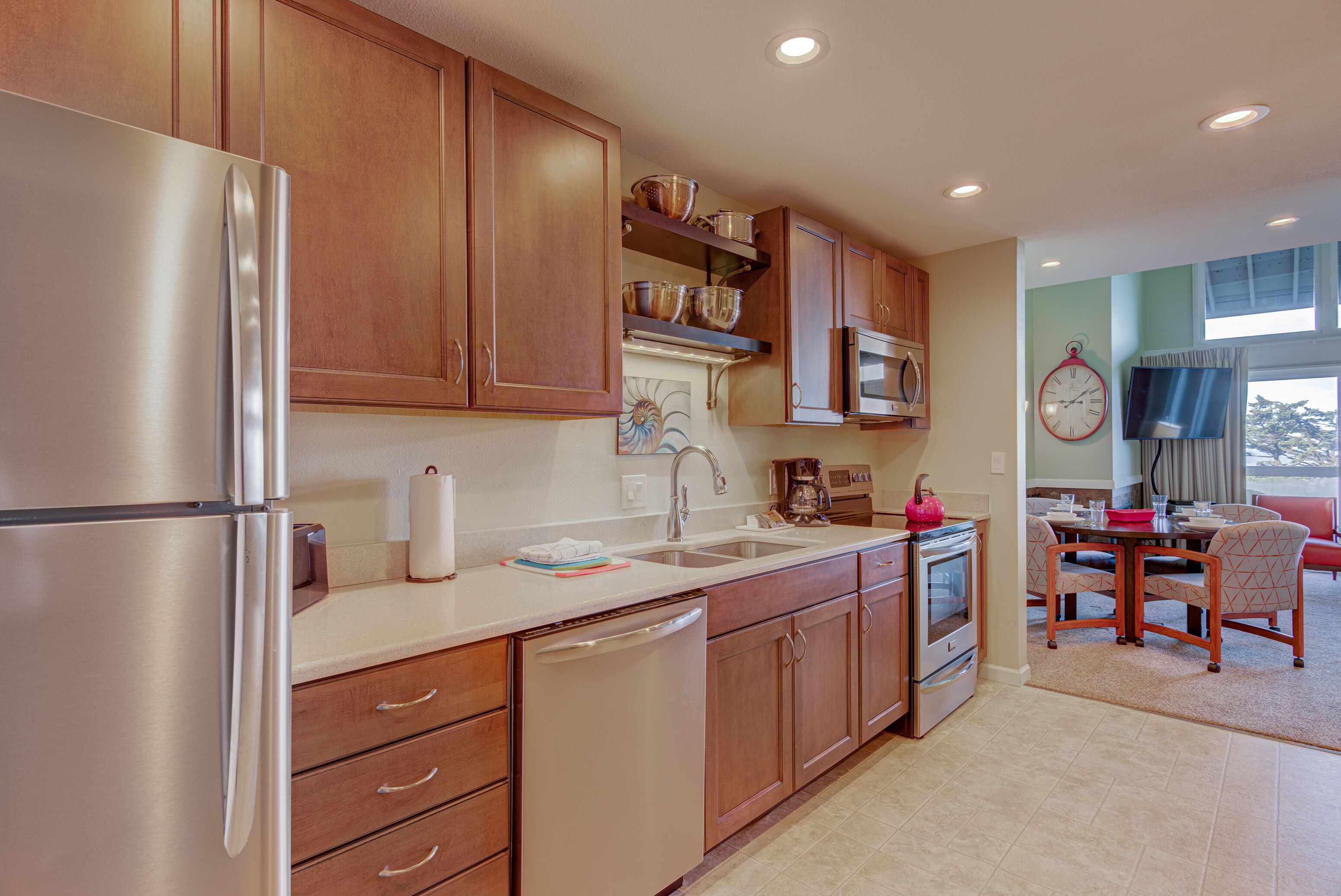 A modern kitchen with stainless steel appliances, wooden cabinets, and a dining area with a table and chairs.