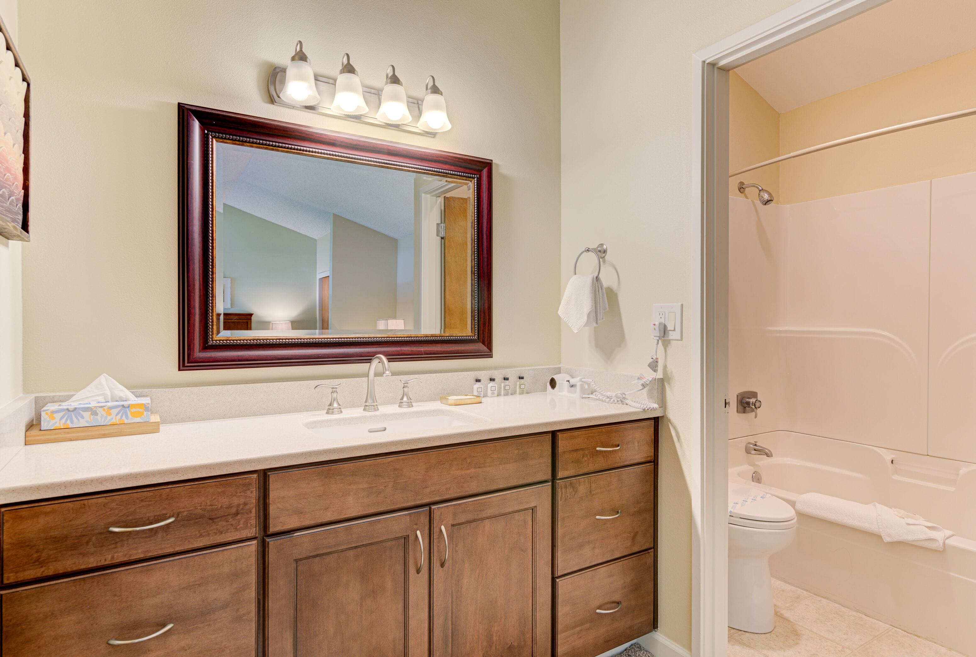 Une salle de bain avec un grand miroir, un lavabo, des meubles en bois, un porte-serviettes et une baignoire.