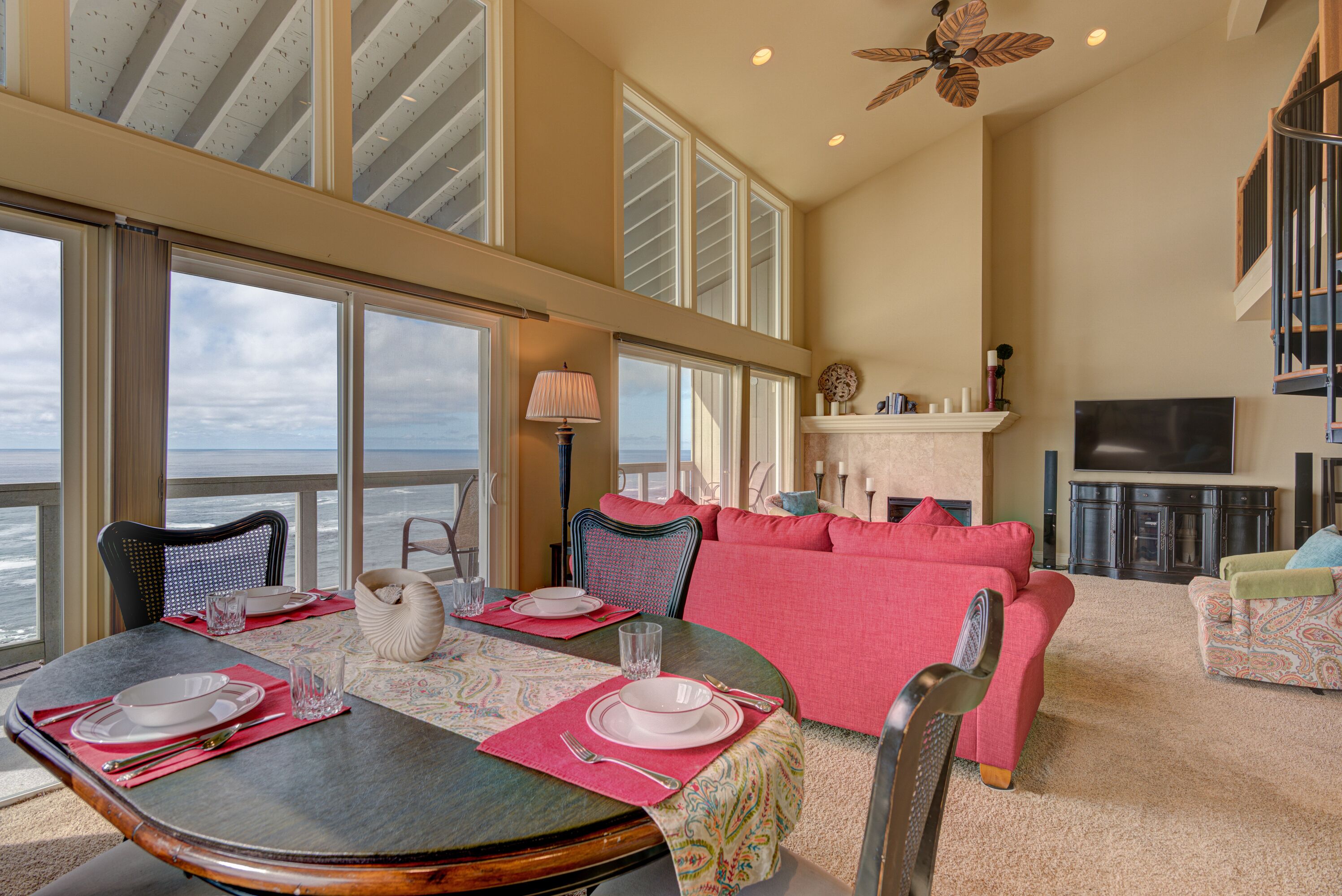 A dining area with a table set for two, a sofa, and a fireplace.