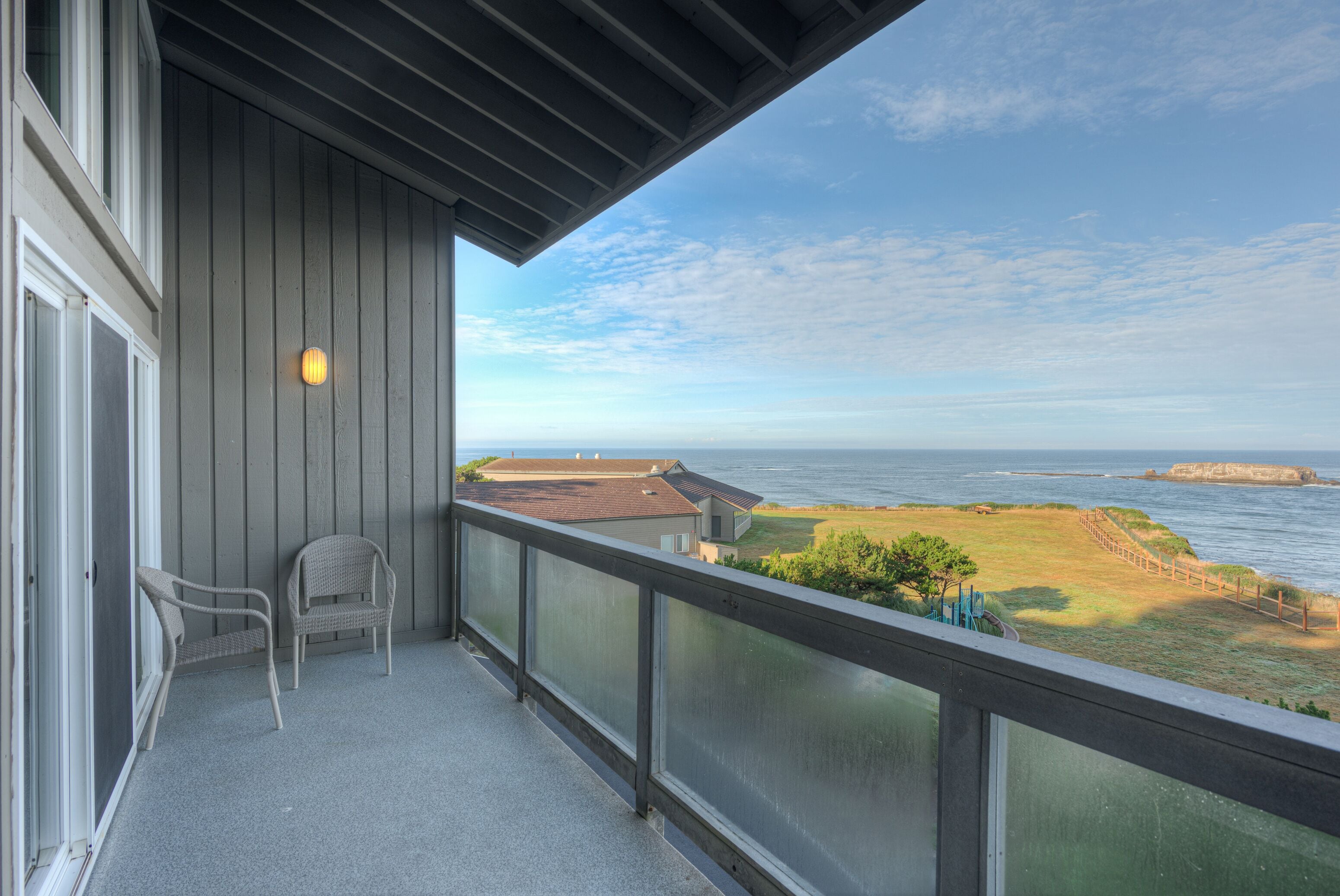 Un balcon avec vue sur l’océan, une chaise et un luminaire.