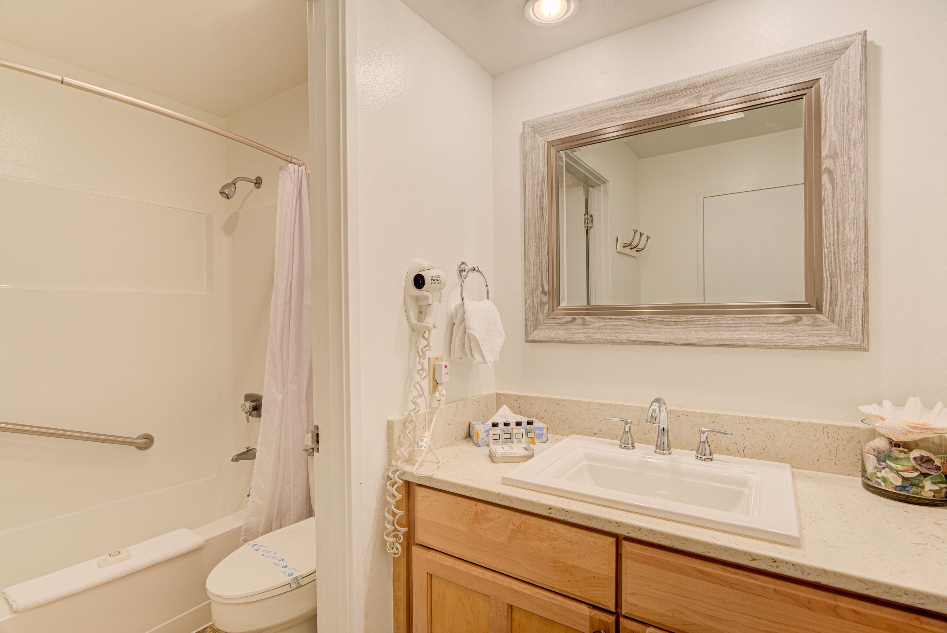 A bathroom with a shower, toilet, sink, and vanity.