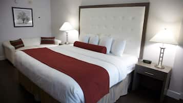 Habitación de hotel con una cama grande, una mesita de noche con lámpara, una mesita auxiliar y un cuadro en la pared.