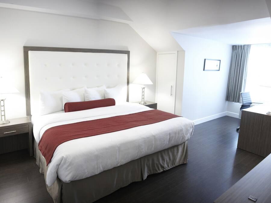 A modern hotel room with a large bed, a desk, and a view of the city.