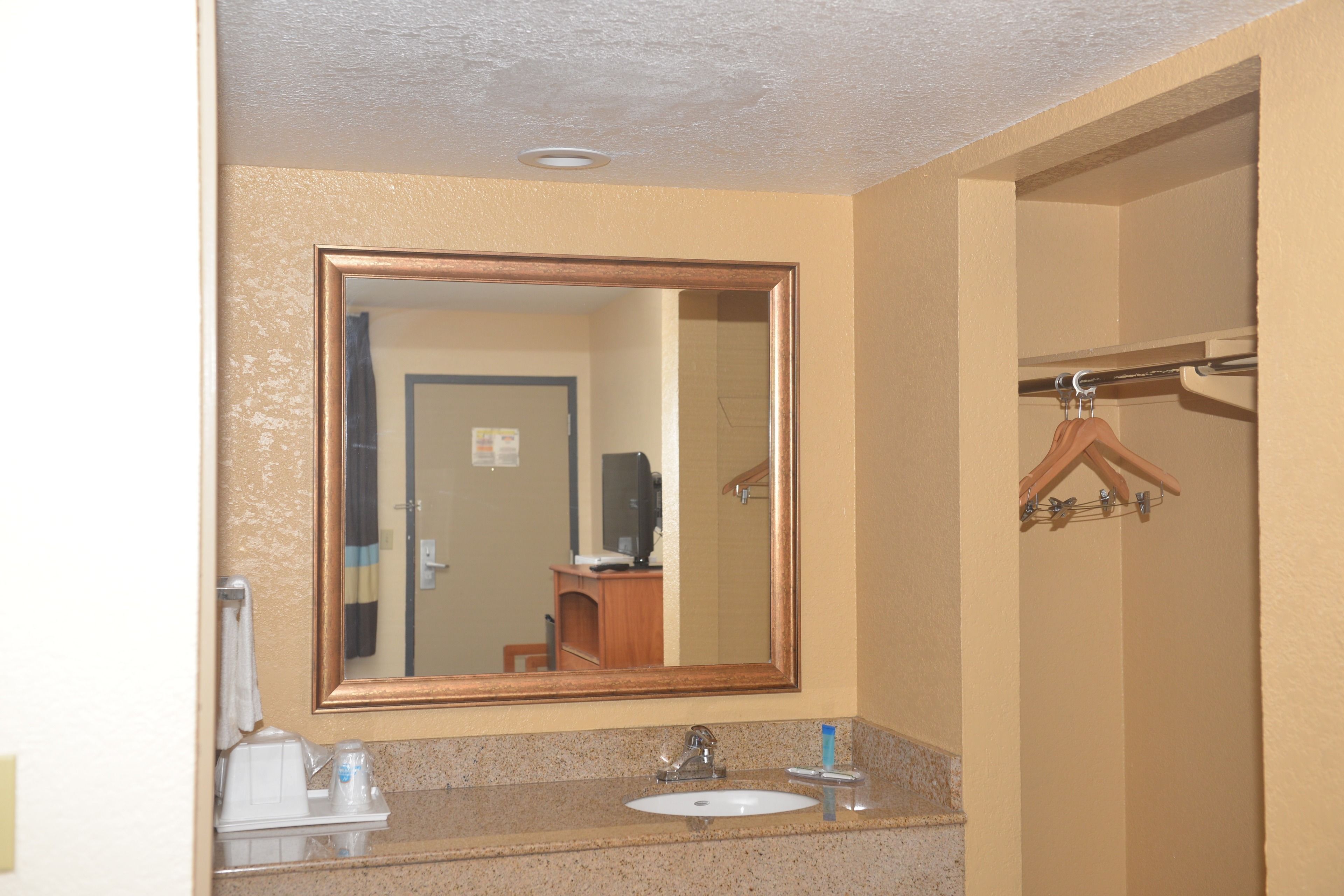 A bathroom with a sink, mirror, and towel rack.