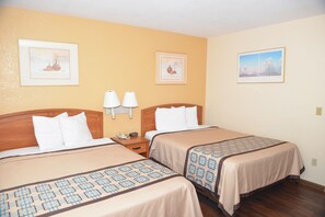 A hotel room with two beds, a nightstand with lamps, and framed artwork on the walls. - Northgate Motel (El Cajon)
