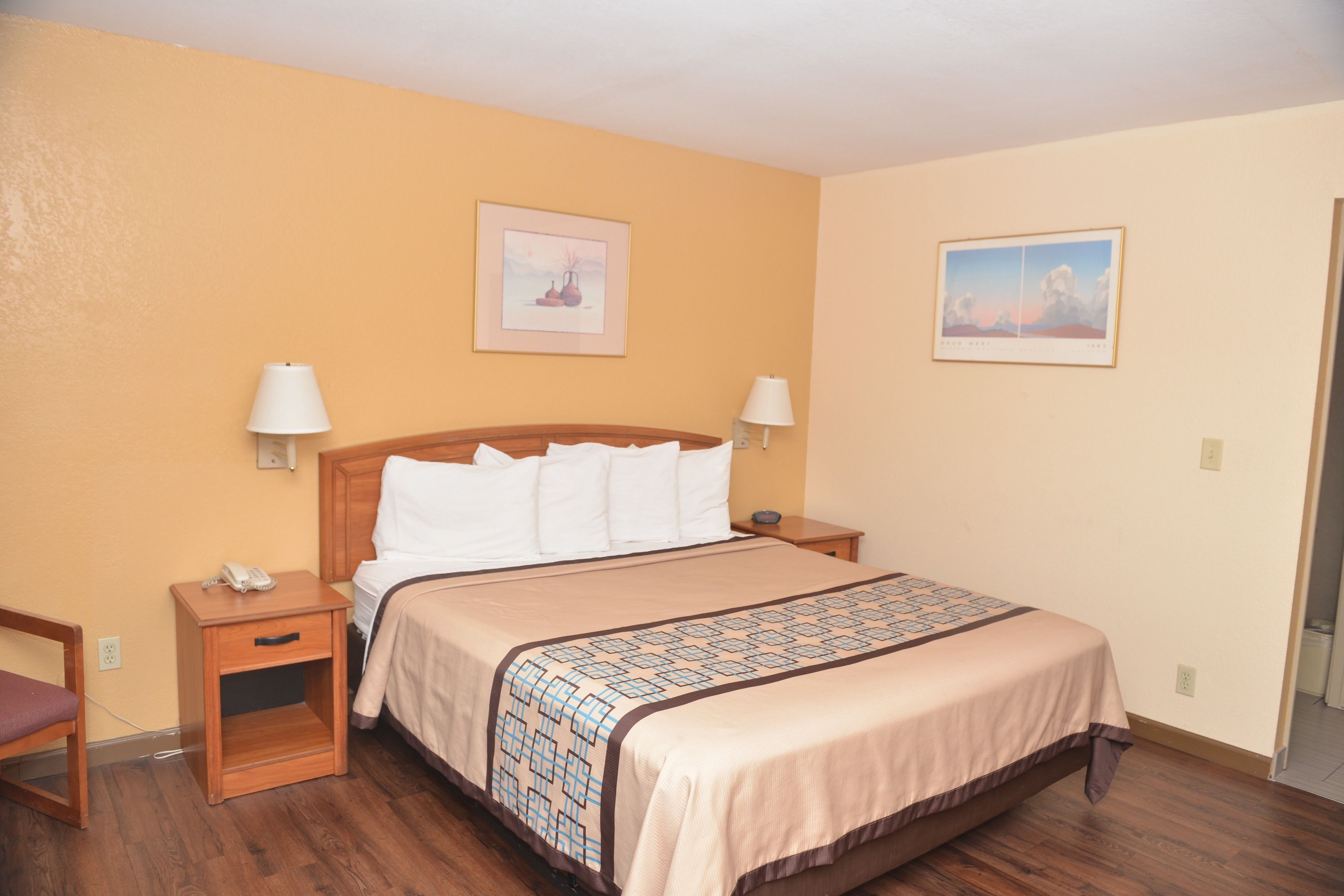 A hotel room with a large bed, two bedside tables, a nightstand, and two wall-mounted lamps.