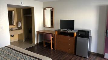 Ein Hotelzimmer mit Bett, Schreibtisch mit Computer, Fernseher, Mikrowelle und kleinem Kühlschrank.
