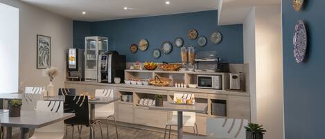 A modern kitchen with a blue accent wall, white cabinetry, and a variety of appliances and decor items.