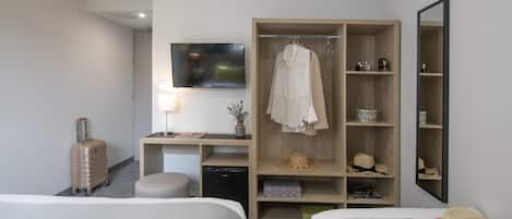A hotel room with two beds, a desk with a TV, a wardrobe, and a mirror.