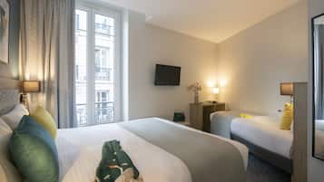 A hotel room with two beds, a TV, bedside lamps, a window with curtains, and a view of the outside balcony.