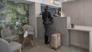 Zona de recepción de diseño moderno, con mostrador de recepción, área de descanso y un mural vegetal en la pared.