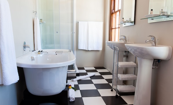 Une salle de bain avec une baignoire, deux lavabos, une douche en verre, un carrelage à motifs et un porte-serviettes.