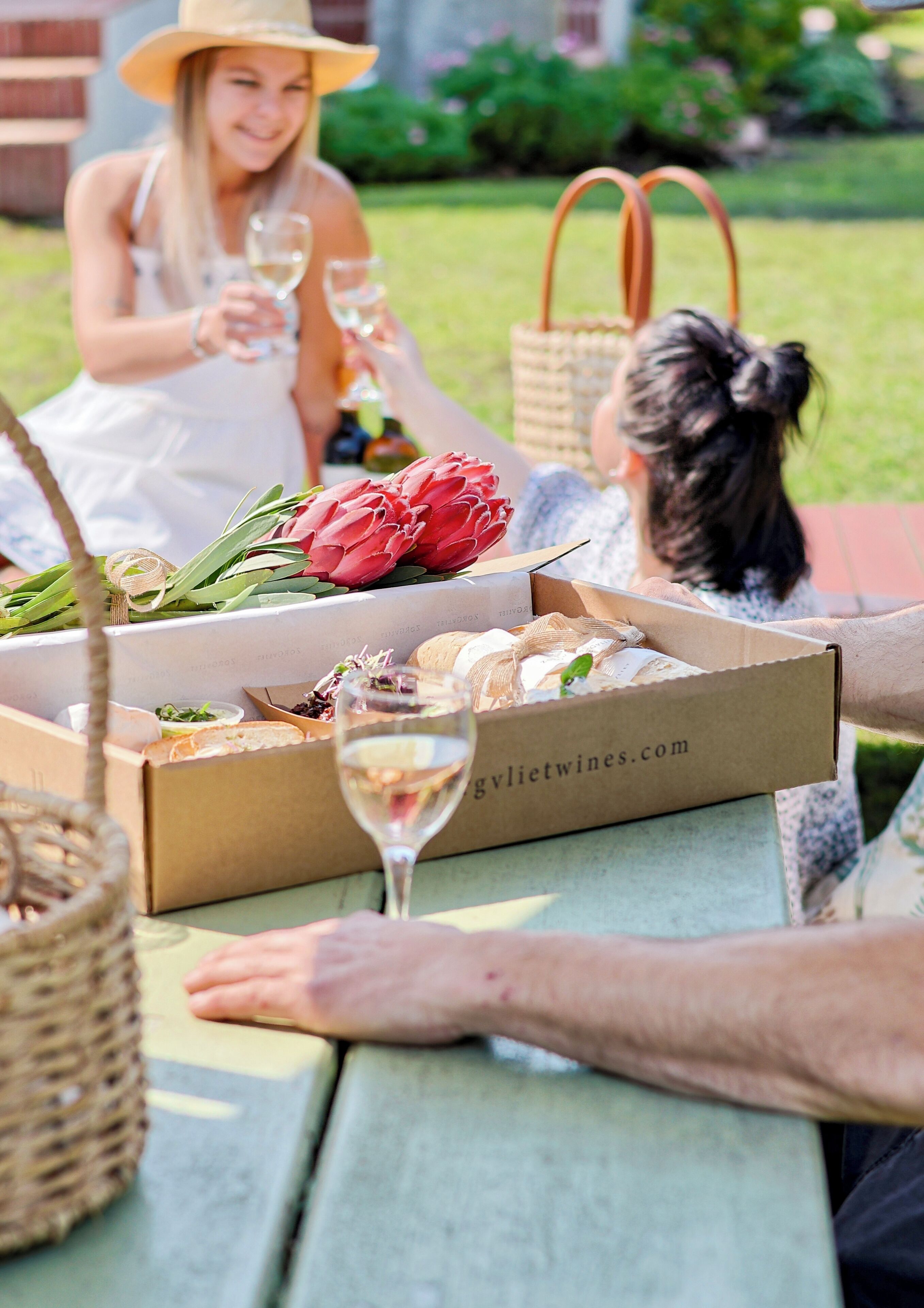 A picnic setup with a table, food boxes, and a wine glass.