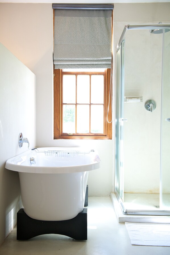 A bathroom with a freestanding bathtub, a window with a view, and a glass-enclosed shower.