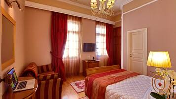 Een hotelkamer met een bed, een bureau met een laptop, een televisie en een lamp.