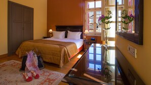 A well-lit bedroom with a large bed, bedside tables, a dresser, and a mirror. - Aetoma Hotel (Nafplio)