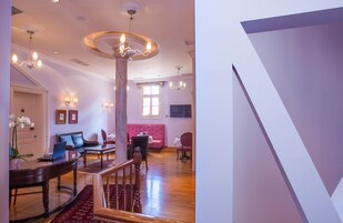 Un espacio habitable amplio con una escalera de madera, un sofá rosa y una mesa de comedor con sillas.