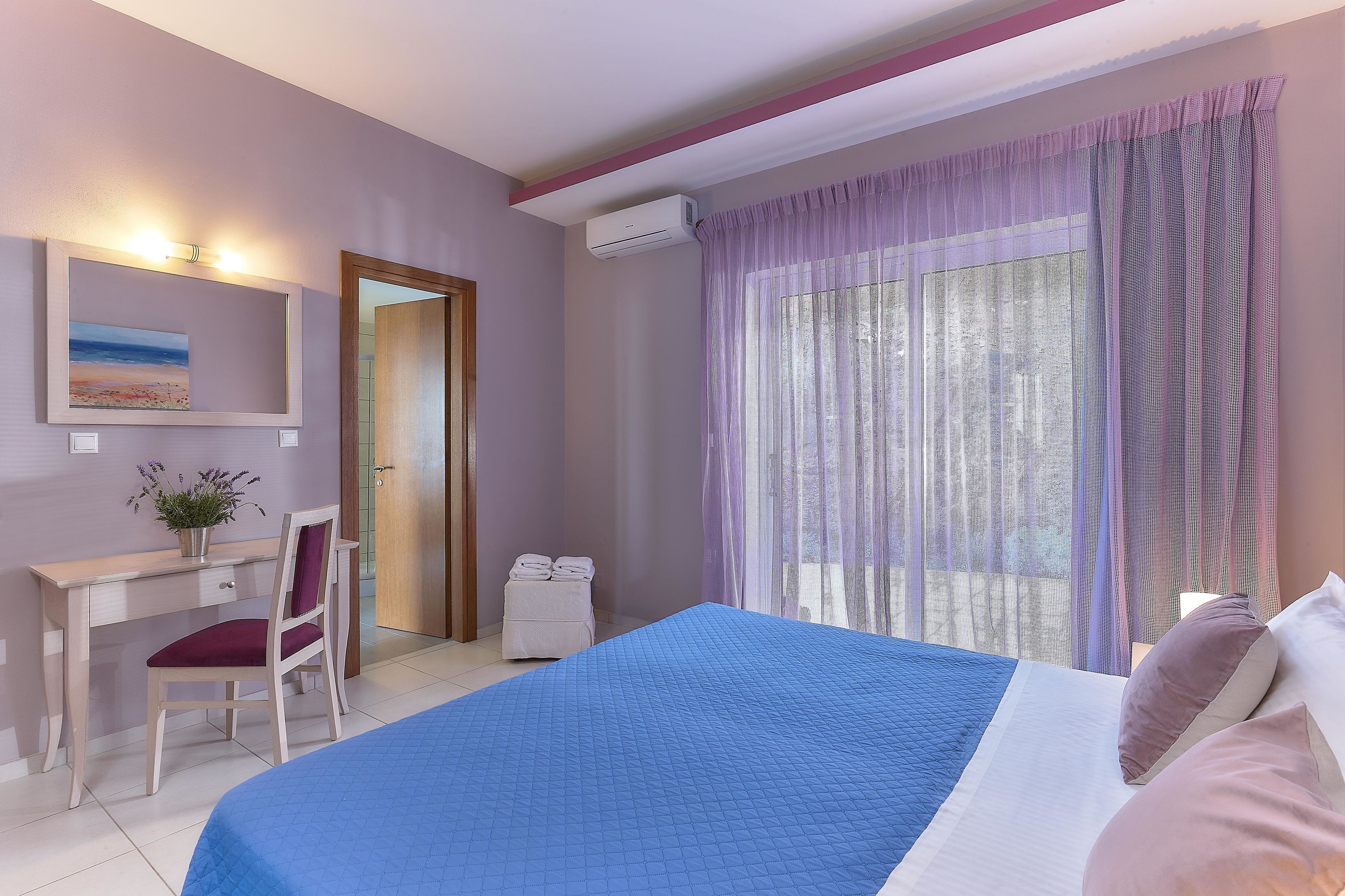 Un dormitorio con cama, escritorio, silla y ventana con cortinas.