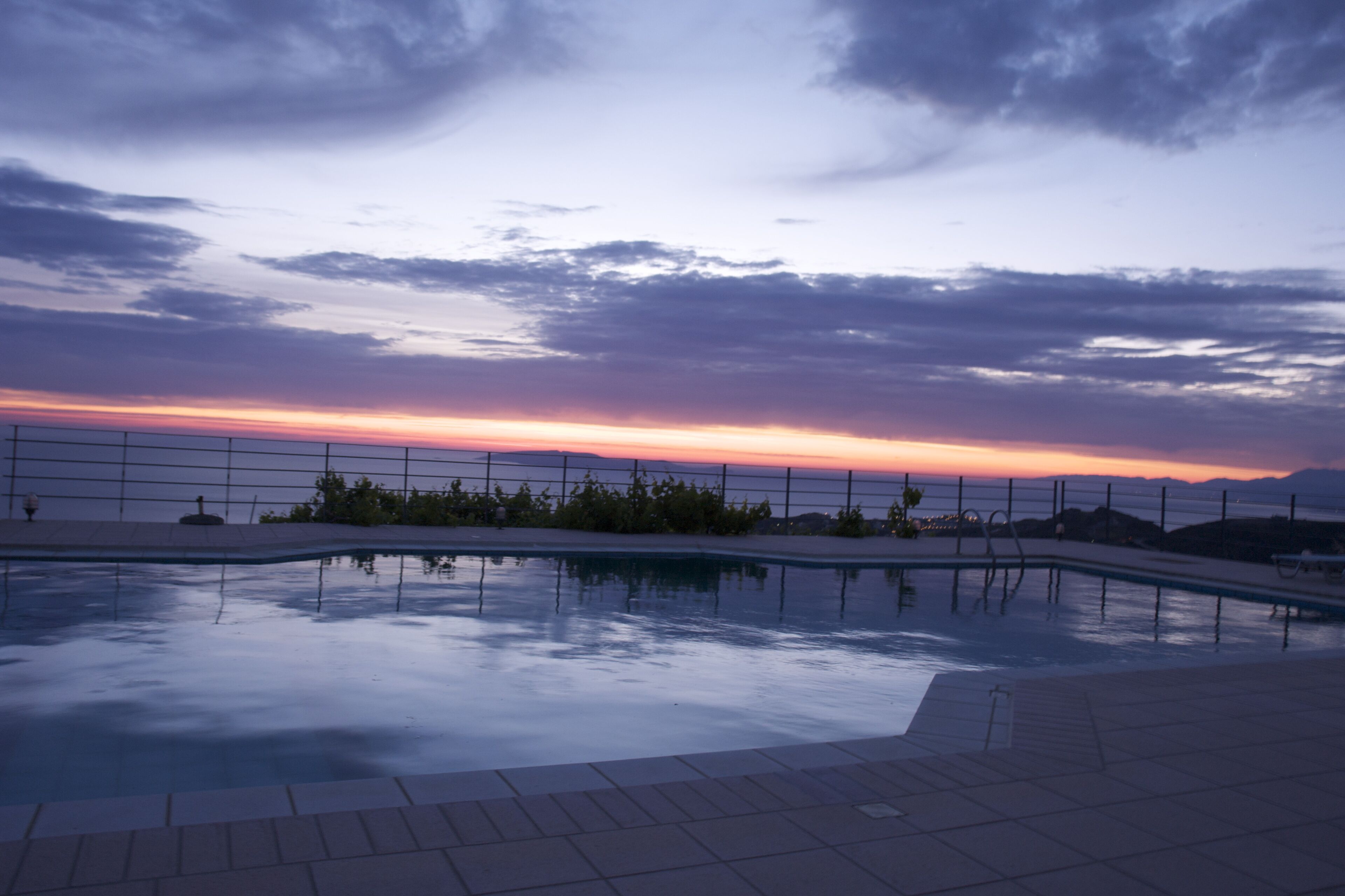 Una piscina con vista al atardecer sobre el océano.