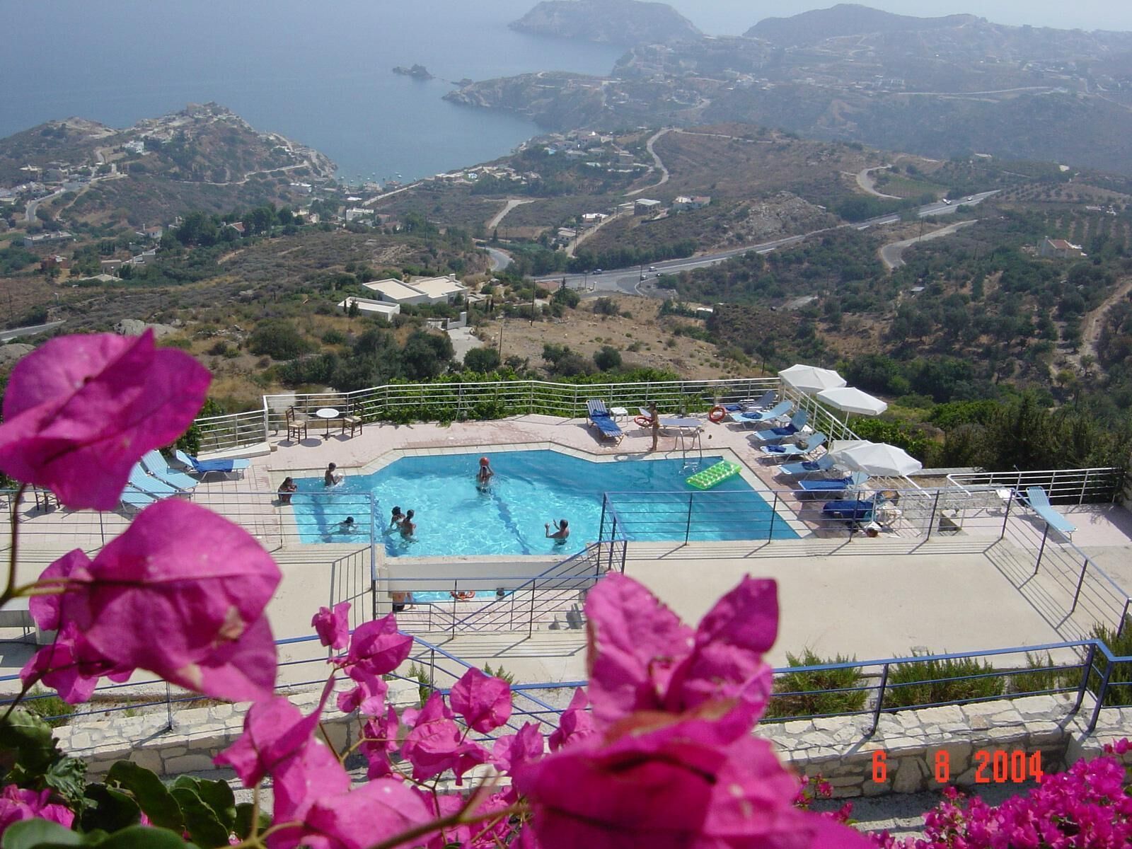 A swimming pool with a view of the sea and hills.