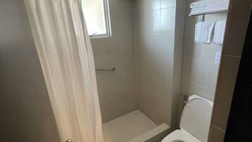A bathroom with a shower, toilet, and towel rack.