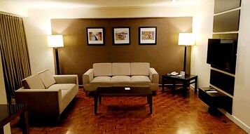 A living room with a sofa, a coffee table, and a TV. There are three framed pictures on the wall.