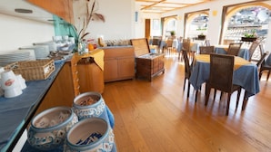 Un comedor con mesas y sillas de madera, una barra de buffet con platos y tazones, y vistas a través de un ventanal de arco.